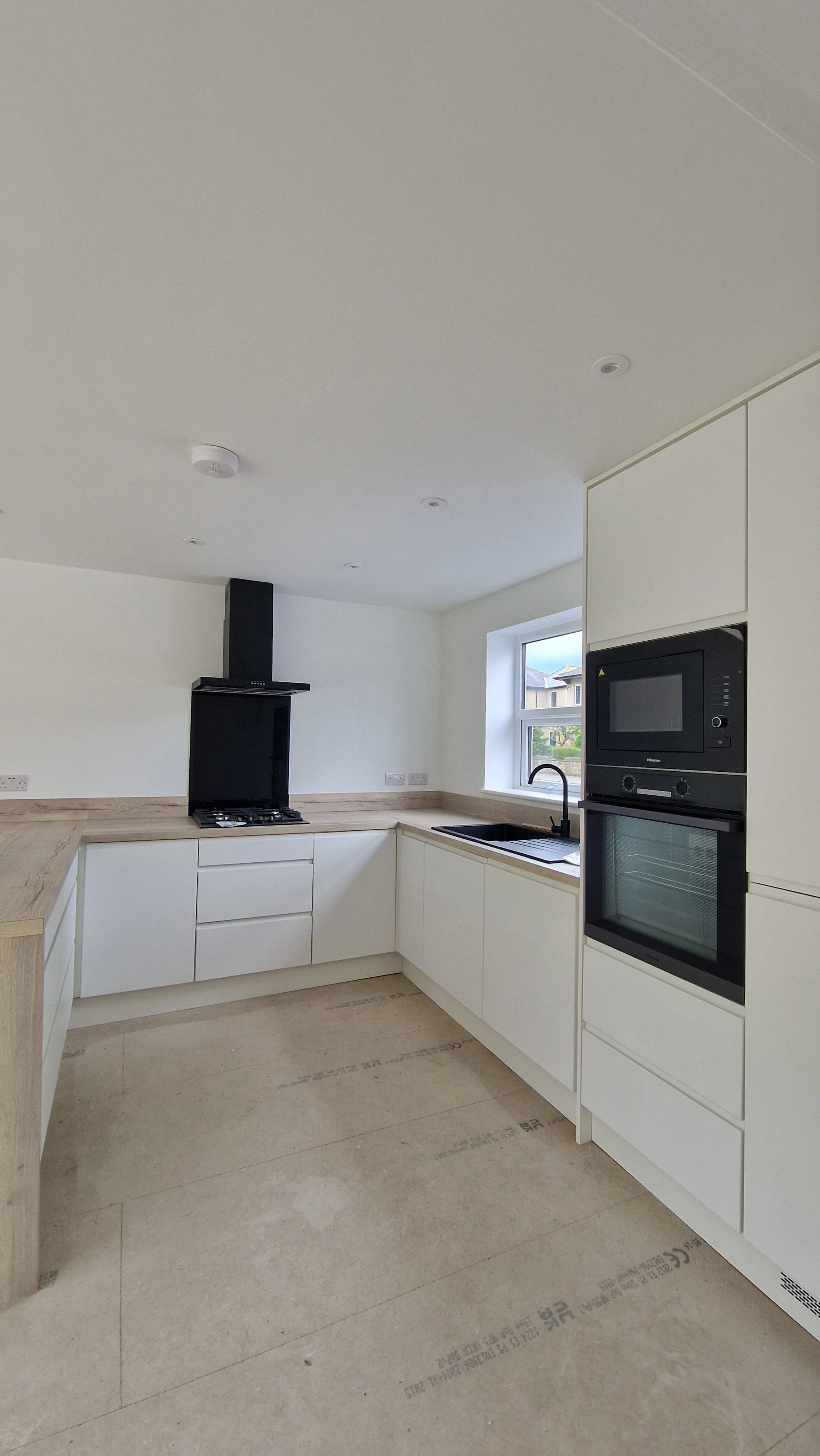 Minimalist white handleless kitchen with black sink