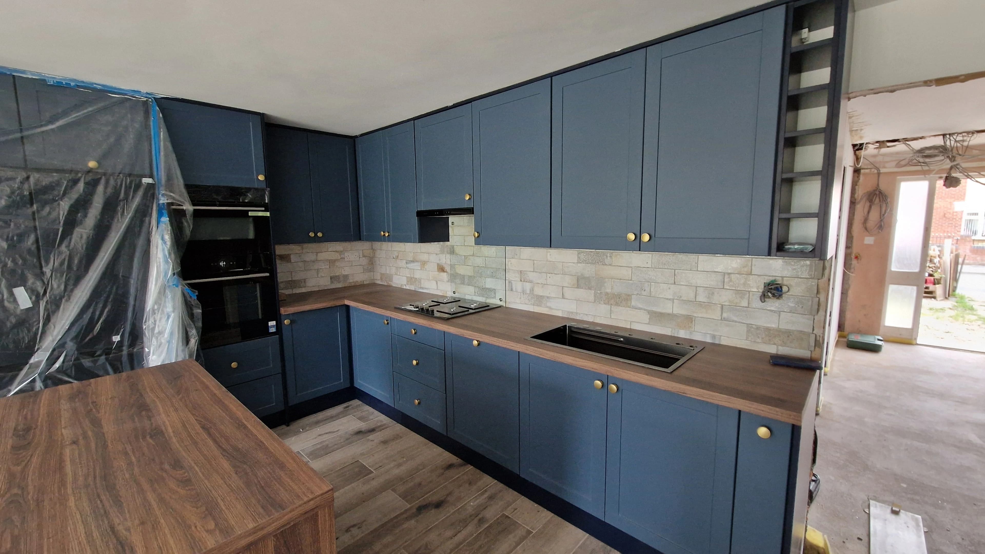 Navy blue shaker kitchen with brick tiles and brass handles