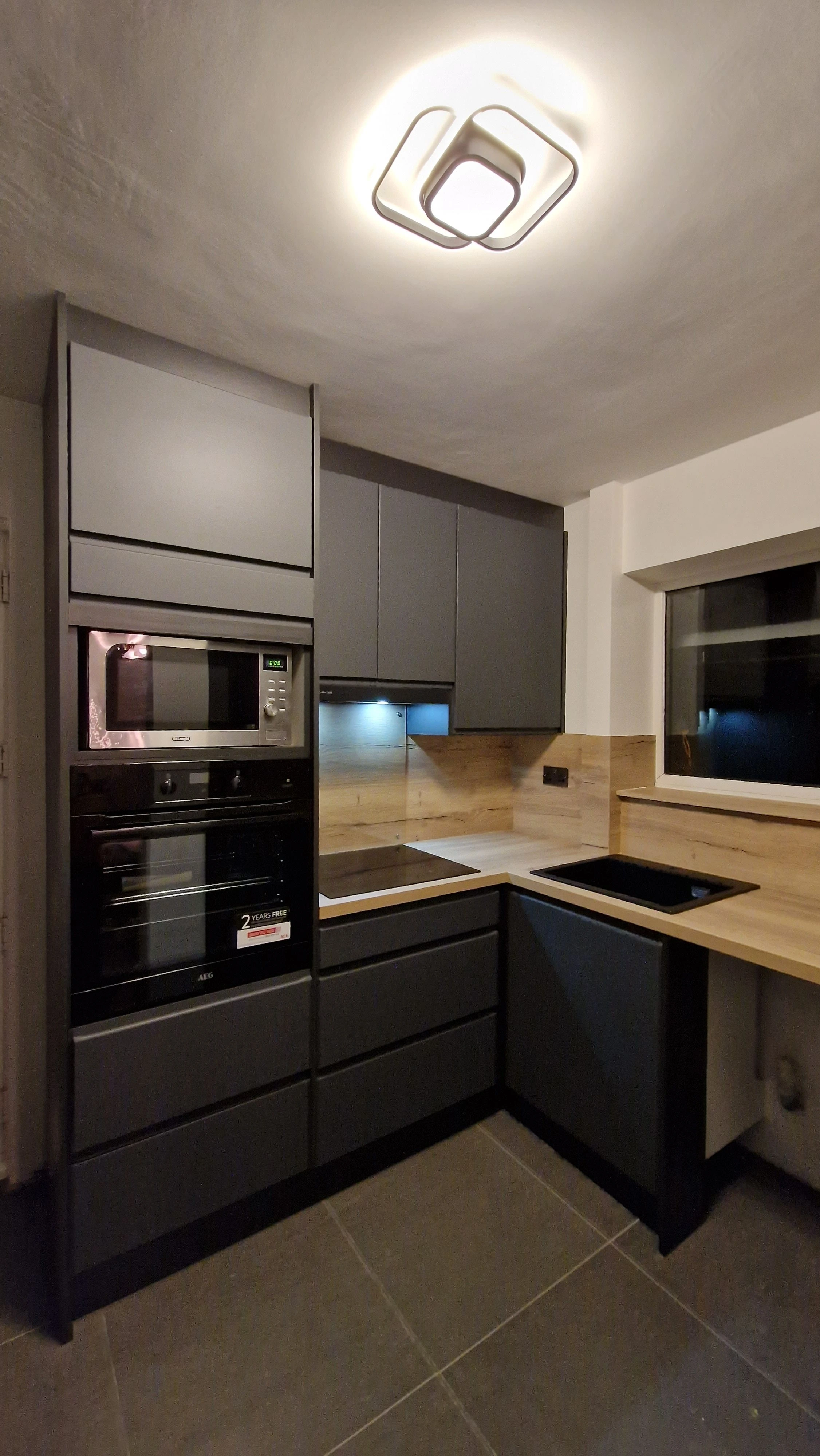 Dark grey matte kitchen with oak backsplash and lighting