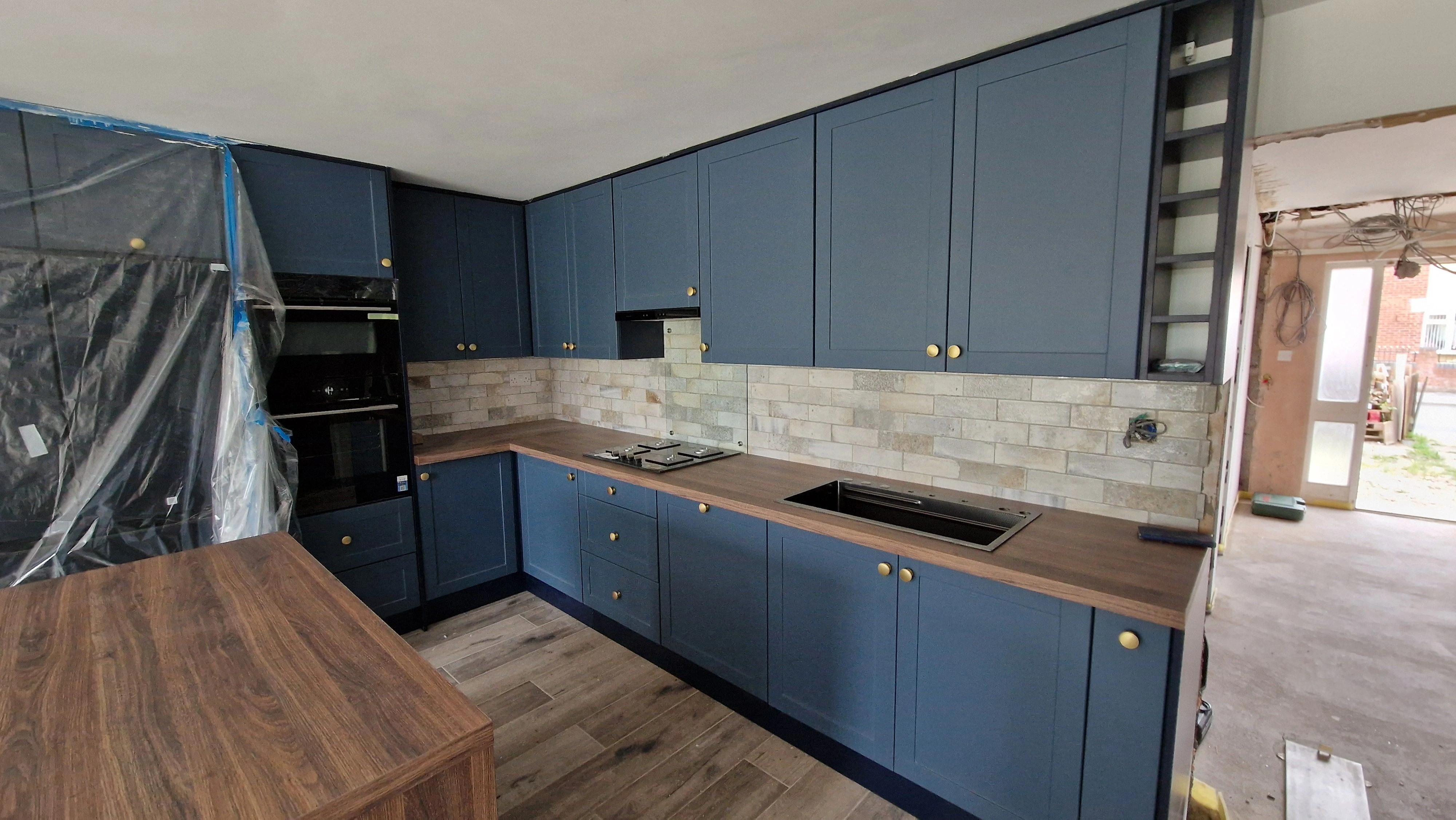 Navy blue shaker kitchen with brick tiles and brass handles