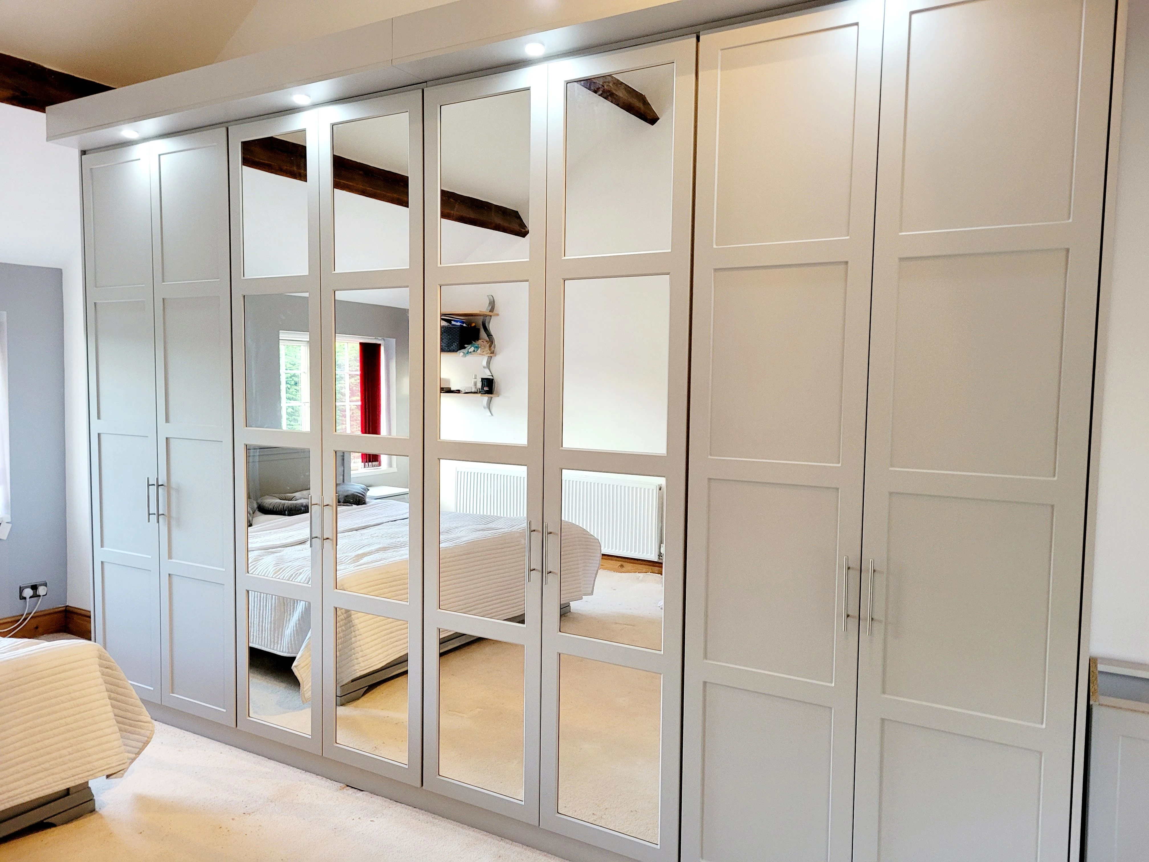 White fitted wardrobe with mirrored grid doors and integrated lighting